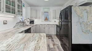 Una cocina moderna con armarios blancos, encimera de mármol y un refrigerador grande con un mapa.