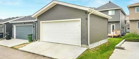 Et hus med garage, indkørsel og græsplæne.