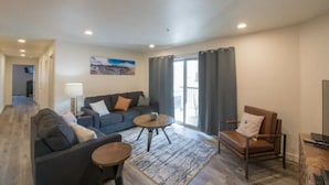 A modern living room with a sofa, armchair, coffee table, and a view of the outdoors. - 4-B The Slick Rock Condo (Ground Floor/Pool Side) (Moab)