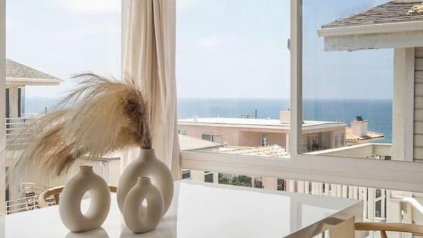 Una habitación moderna con un ventanal grande, una mesa blanca y dos sillas.