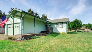 Een gelijkvloers huis met een veranda, garage en een verzorgd gazon.