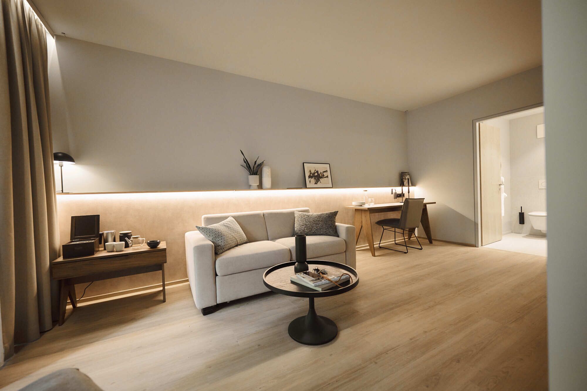 Ein modernes Wohnzimmer mit Sofa, Couchtisch und Schreibtisch.