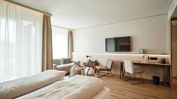 Een moderne hotelkamer met een groot bed, een bureau, een stoel en een aan de muur bevestigde televisie.