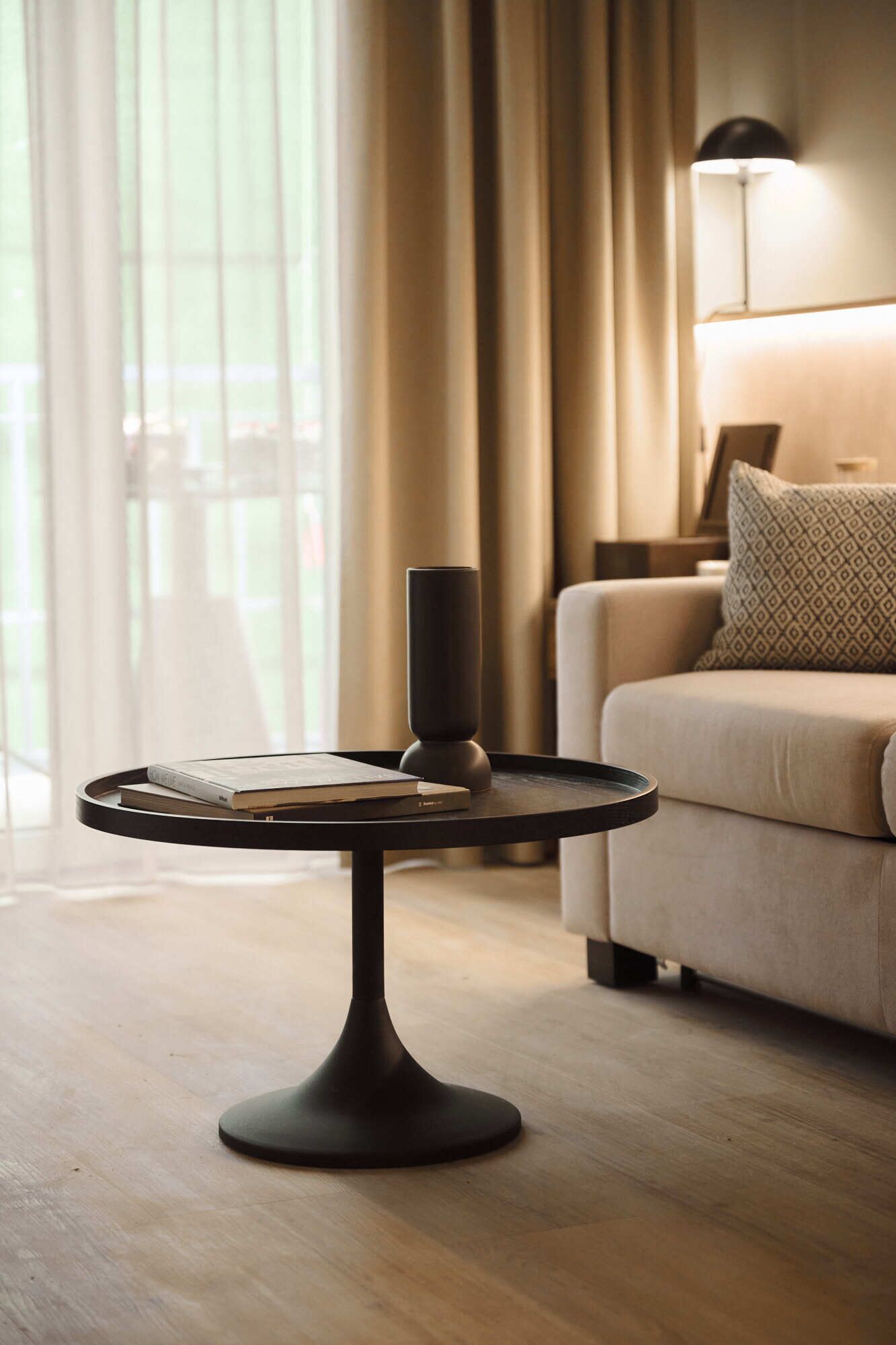 Een moderne woonkamer met een ronde tafel, een lamp en een bank.