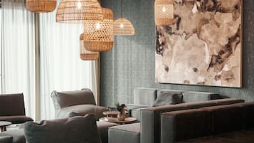Un área de descanso moderna con sofás de cuero, mesas redondas de madera y lámparas colgantes tejidas.