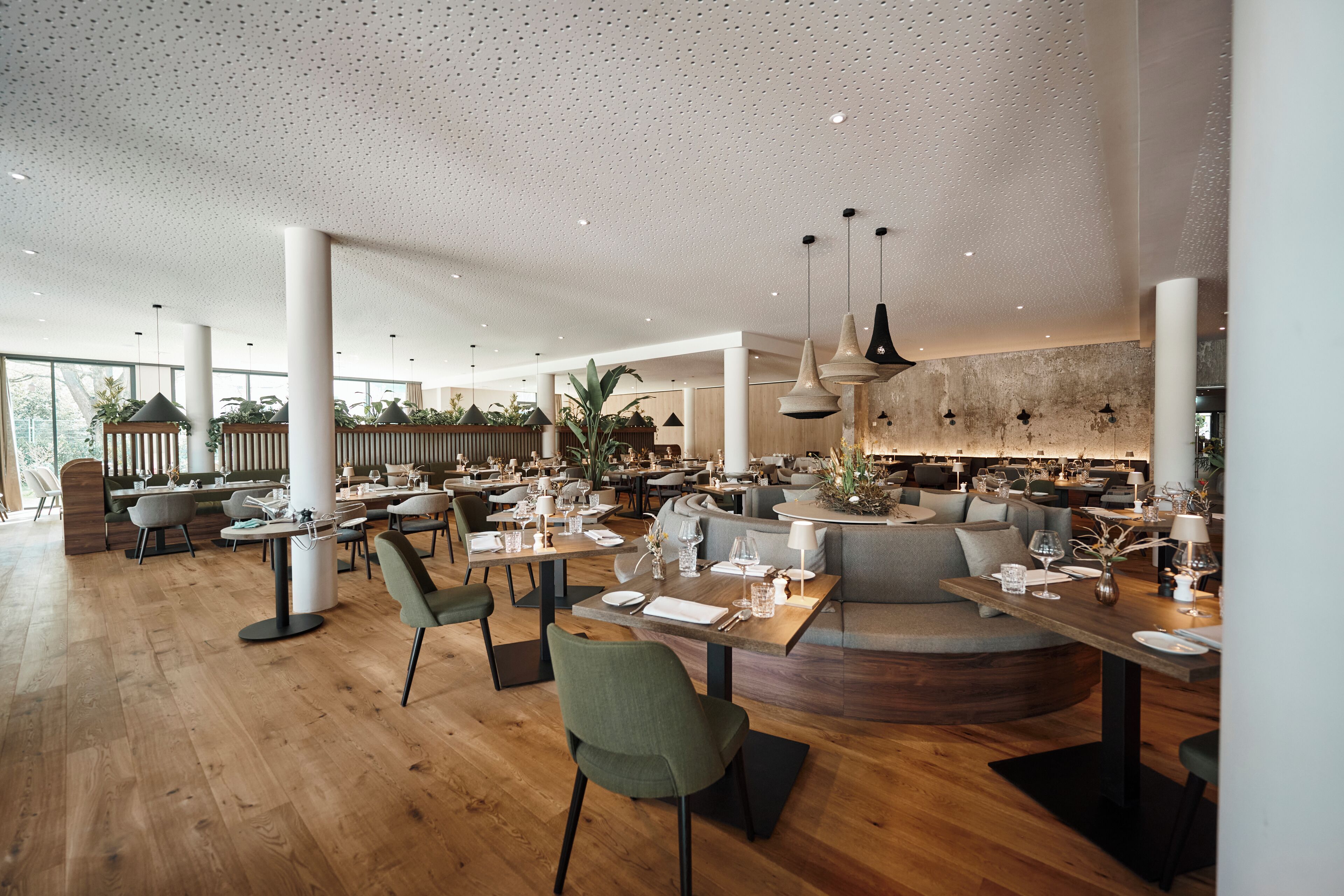 A spacious restaurant with high ceilings, wooden floors, and modern furniture.
