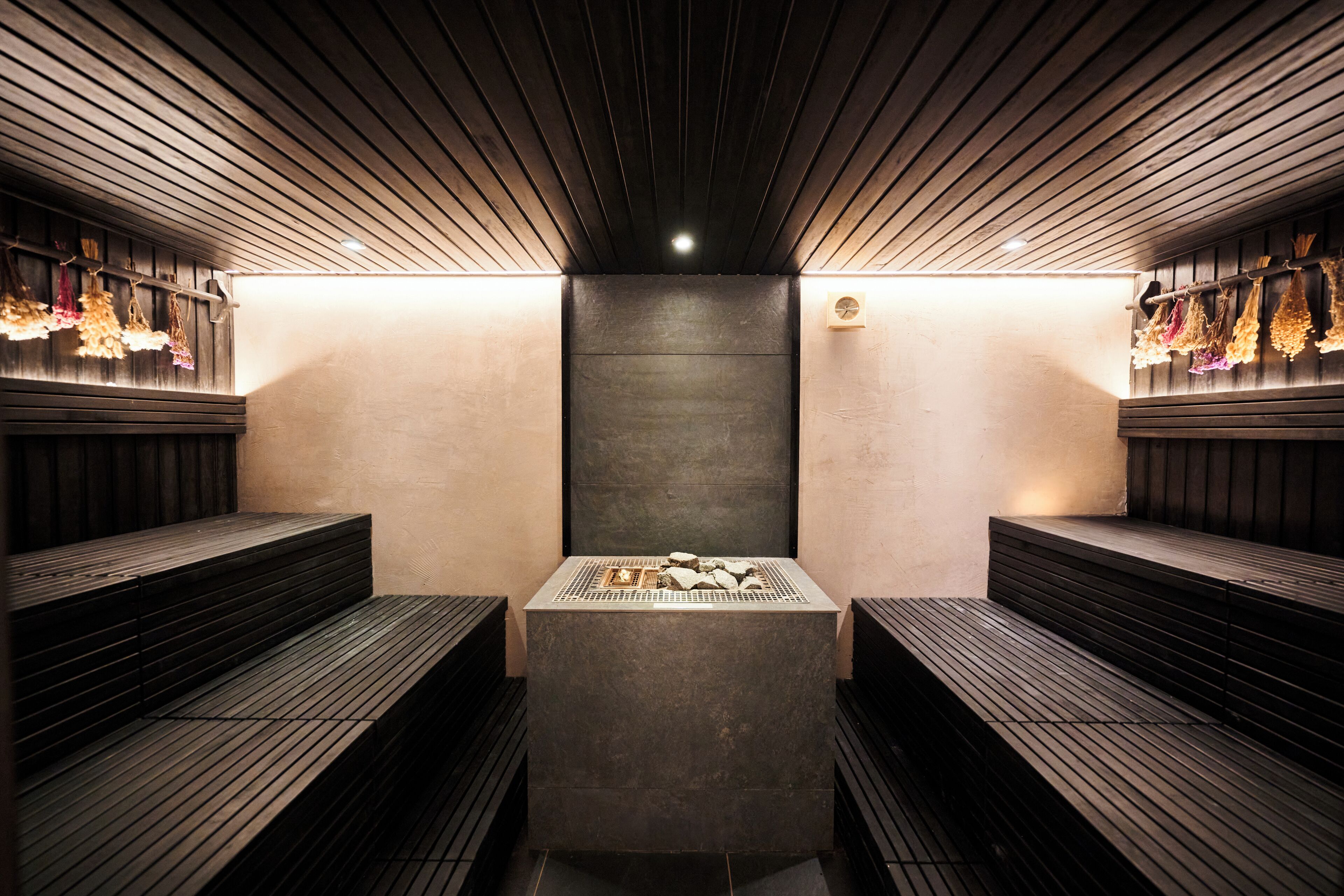 Una sauna con bancos de madera y una plataforma central de piedra climatizada.