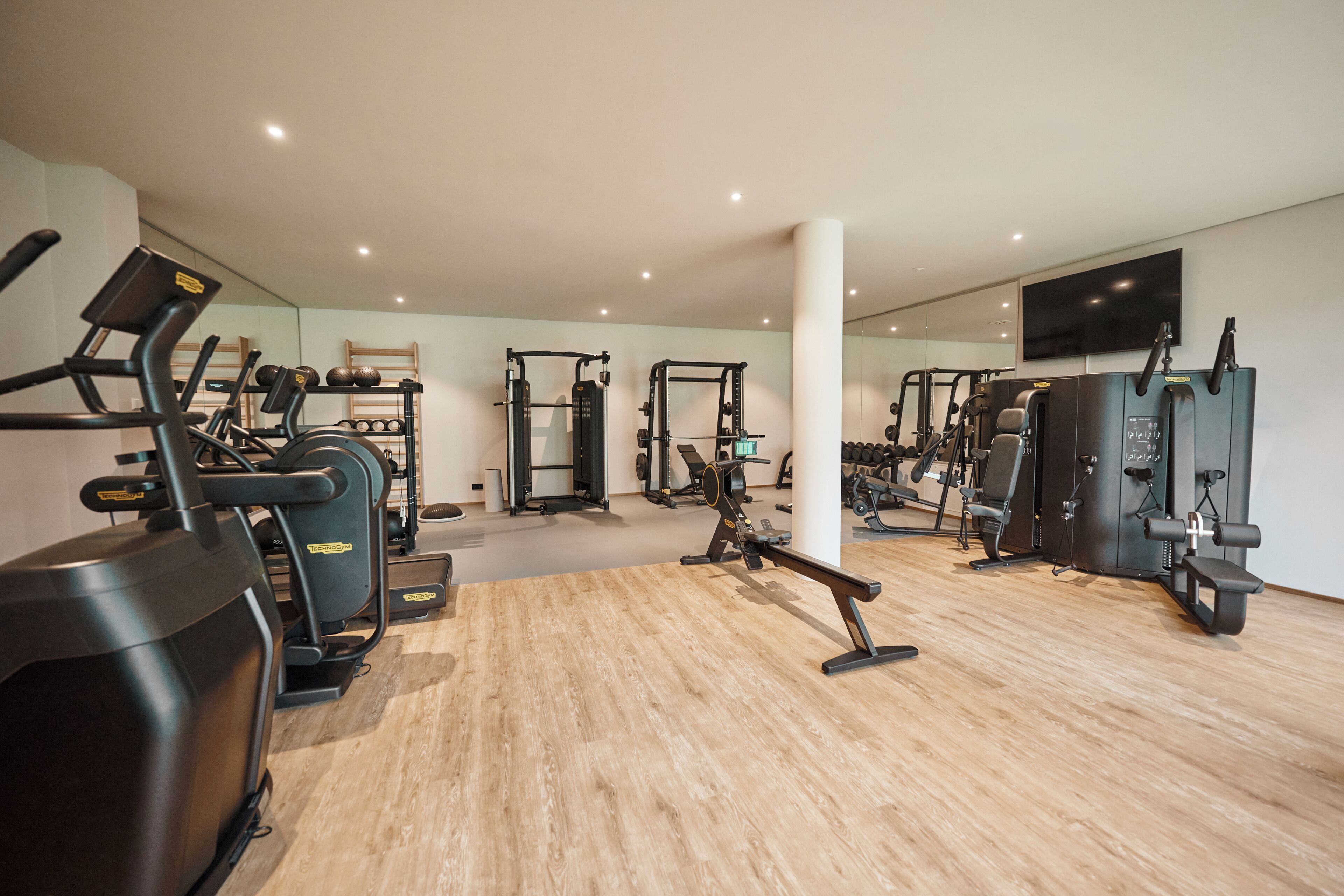 A gym with cardio machines, weightlifting equipment, and a mirrored wall.