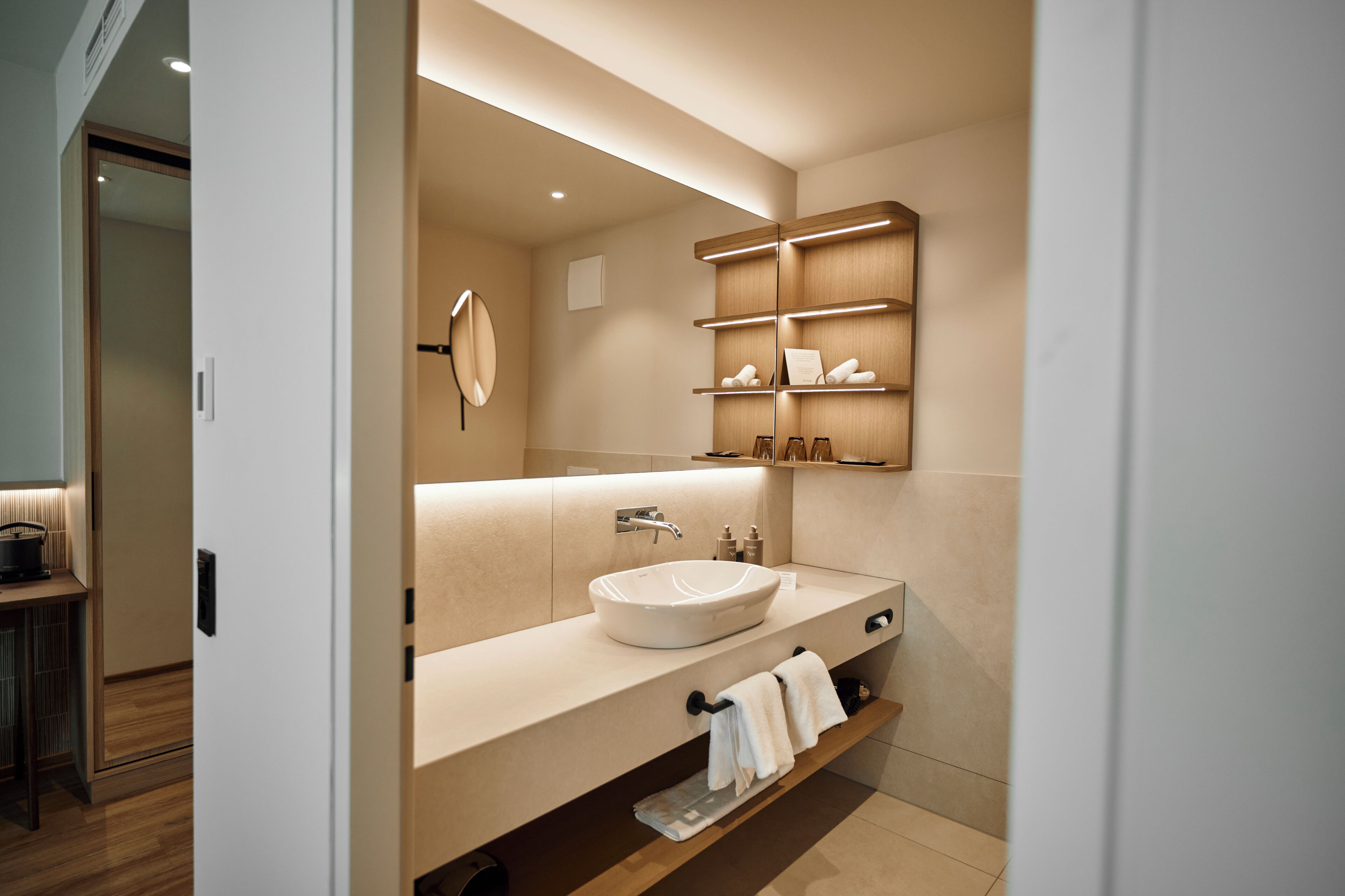 Un baño moderno con un lavamanos grande, toalleros y estantes para artículos de aseo.
