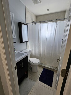 A bathroom with a white toilet, a sink, and a shower curtain. - Minutes from the downtown life of Delray Beach and a mile away from the beach! (Delray Beach)