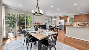 A modern kitchen with a central island, wooden flooring, and a dining area with a large table and chairs. - Pet-friendly, large yard, flexible extensions (Arlington)