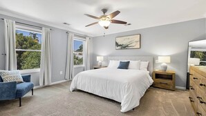 A bedroom with a large bed, two bedside tables, a ceiling fan, and a window with curtains. - Pet-friendly, large yard, flexible extensions (Arlington)