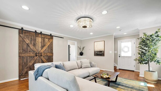 A living room with a sectional sofa, a coffee table, a chandelier, and a sliding barn door. - Pet-friendly, large yard, flexible extensions (Arlington)