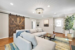 A living room with a sectional sofa, a coffee table, a chandelier, and a sliding barn door. - Pet-friendly, large yard, flexible extensions (Arlington)