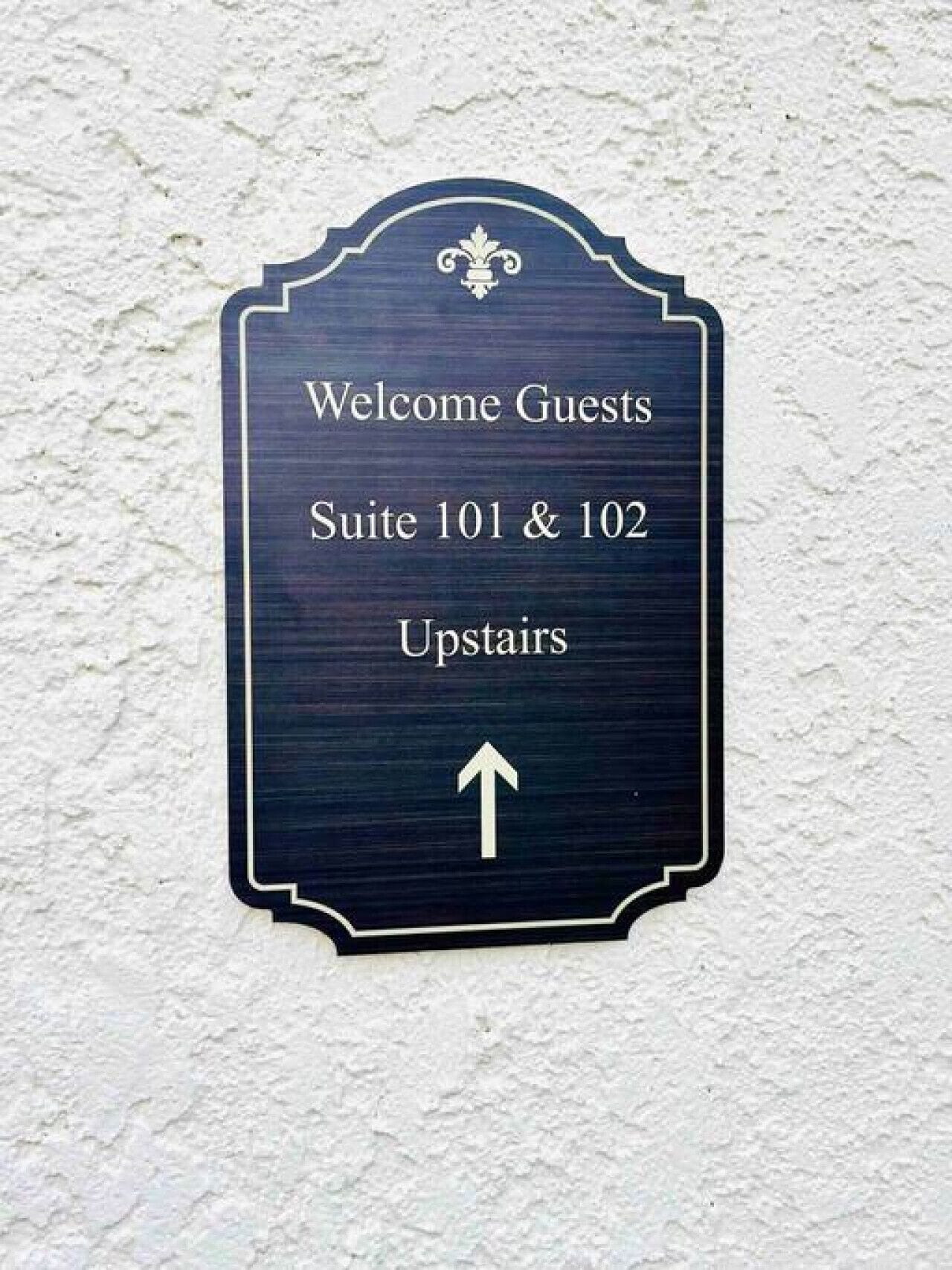 A sign indicating 'Welcome Guests Suite 101 & 102 Upstairs' with an arrow pointing upwards.