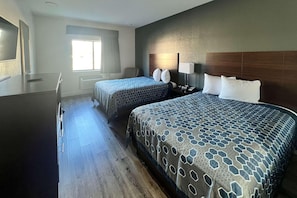 Habitación de hotel con dos camas, un escritorio, una silla, un ventanal y una lámpara fijada a la pared.