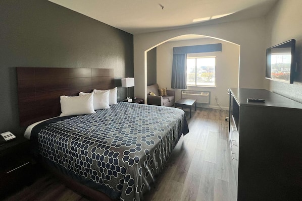 A hotel room with a large bed, a desk, a chair, a TV, and a window with a view.