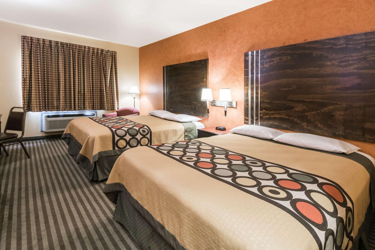 A hotel room with two beds, a desk, and a chair.