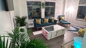 A modern living room with a sofa, coffee table, and potted plants. - Luxurious Downtown Indy City View Apartment!  (Indianapolis)