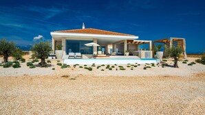 A modern house with a pool, outdoor seating, and a view of the sea. - Villa La Isla with Pool II (Novalja)