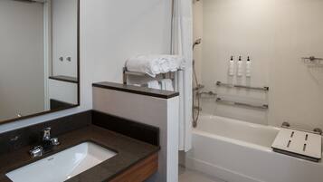 Une salle de bain moderne équipée d’un lavabo, d’un miroir, d’une douche et d’un porte-serviettes.