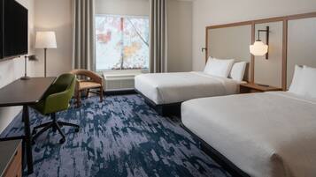 A hotel room with two beds, a desk, a chair, a TV, and a window with curtains.