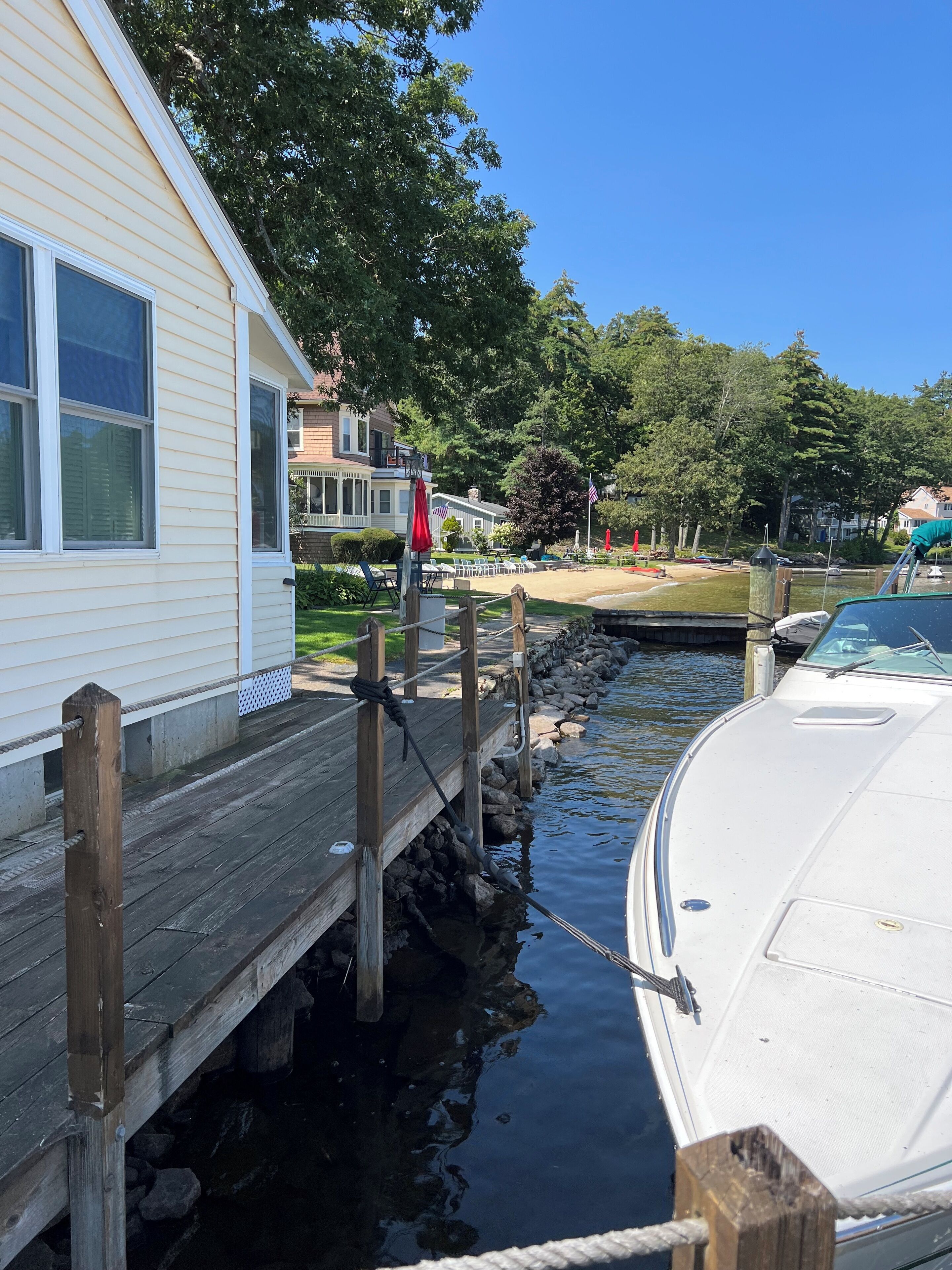 Ein Steg mit einem Boot, eine Holzpier und ein Haus mit weißer Fassade.