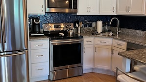 A modern kitchen with white cabinets, stainless steel appliances, and a wooden floor. - 2 Bed/1 Bath Saunders Bay Gilford with boat slip. Walk to Meadowbrook for a show (Gilford)