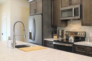 Fully equipped kitchen with stainless steel appliances, dark wood cabinets, and modern faucet.