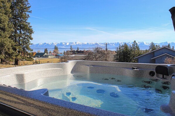 Relax in a hot tub surrounded by serene natural scenery and breathtaking mountain views.