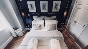 A hotel room with a large bed, two bedside tables, a wall-mounted artwork, and a door. - The Apartment, Broadway (Broadway)