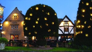The Broadway Hotel with a traditional architecture, a well-lit outdoor seating area, and a neatly landscaped garden. - The Apartment, Broadway (Broadway)