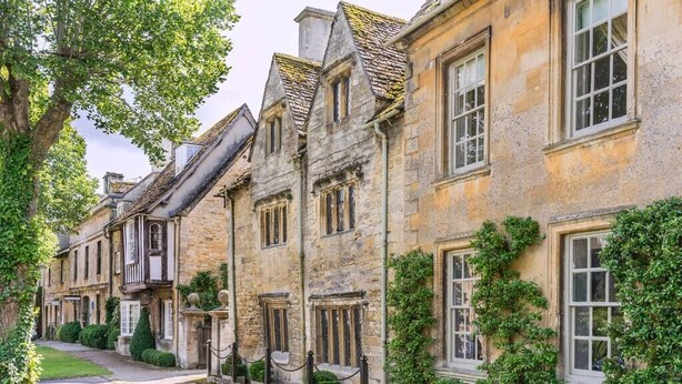 A row of stone buildings with traditional architecture, including gabled roofs and multiple windows. - The Apartment, Broadway (Broadway)