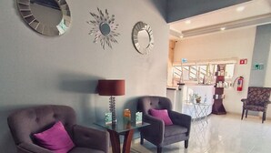 A lobby with two armchairs, a glass-top table, and decorative mirrors on the wall. - Noas hotel (Matamoros)