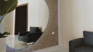 A modern living room with a large mirror, a sofa, and a potted plant. - Noas hotel (Matamoros)