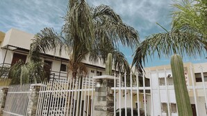 A building with a white exterior, a stone wall, and a white metal fence. - Noas hotel (Matamoros)