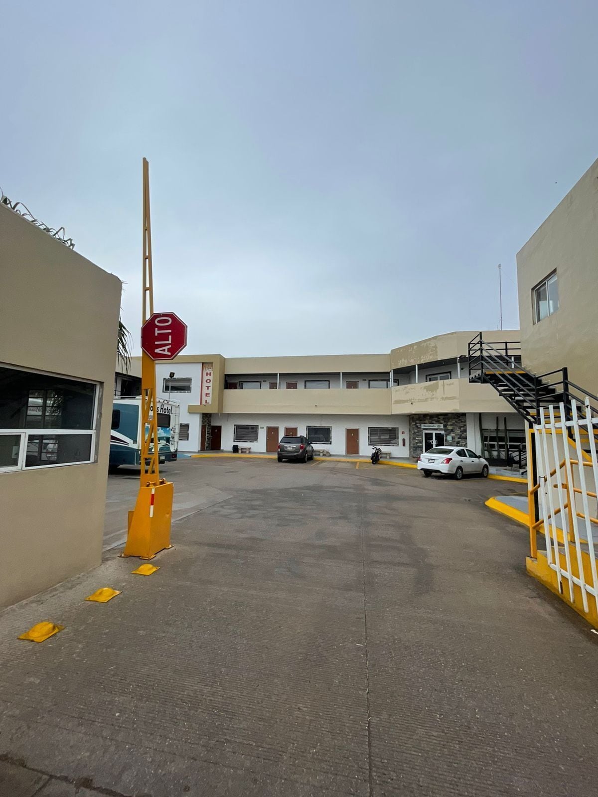 Un motel con aparcamiento, una señal de stop y una escalera que conduce a un nivel superior.