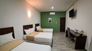 A hotel room with three beds, a desk, a chair, a TV mounted on the wall, and an air conditioning unit. - Noas hotel (Matamoros)