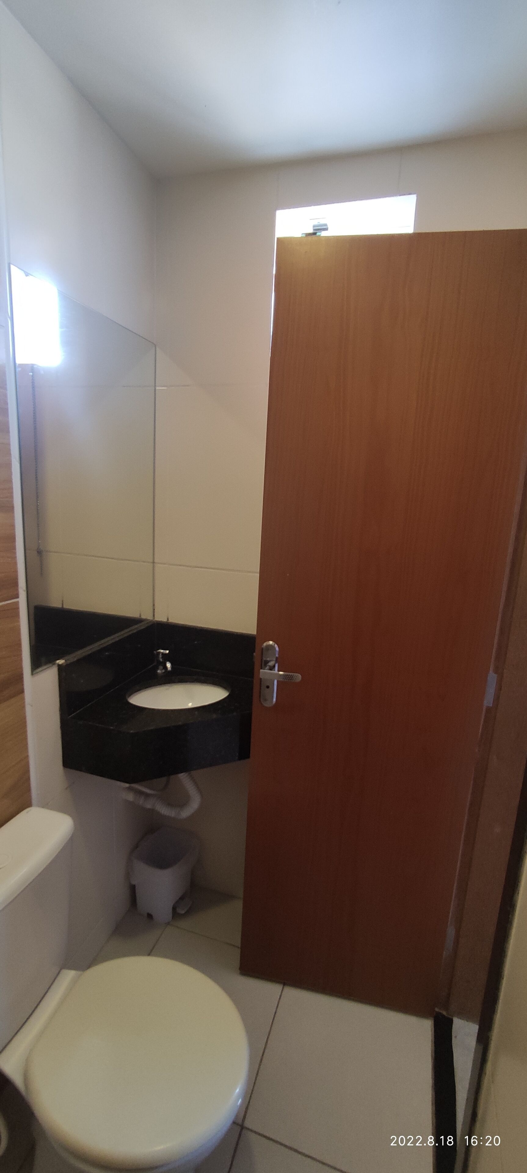 A small bathroom with a white toilet, a black sink, and a wooden door.