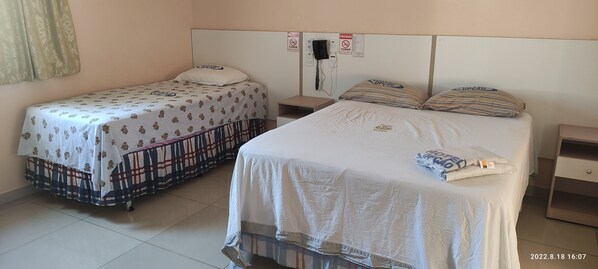 Two single beds with patterned bedding, a bedside table, a phone, and a sign prohibiting smoking. - Hotel Madu (Manaus)