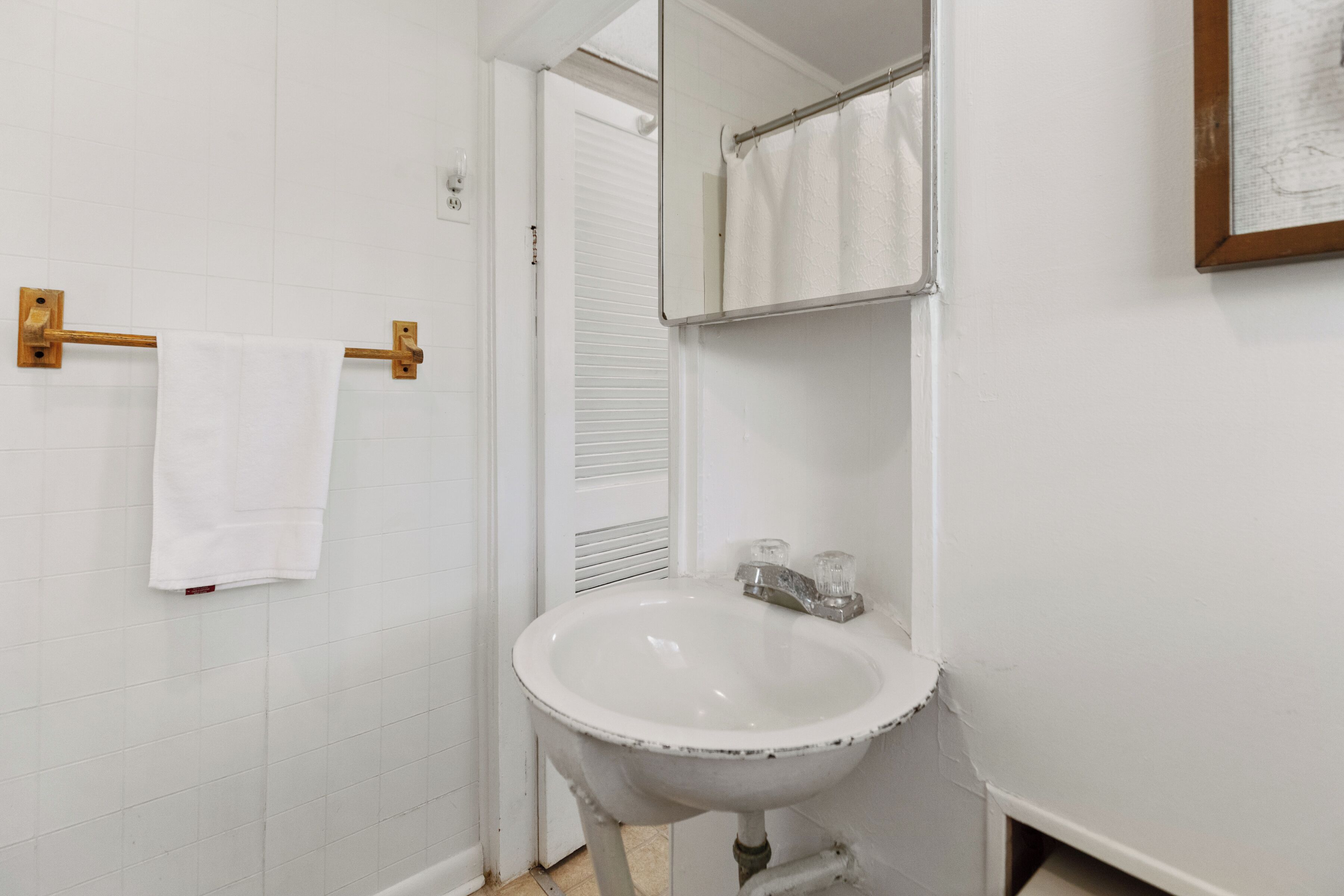 A bathroom with a white sink, a towel rack with a white towel, and a mirror.
