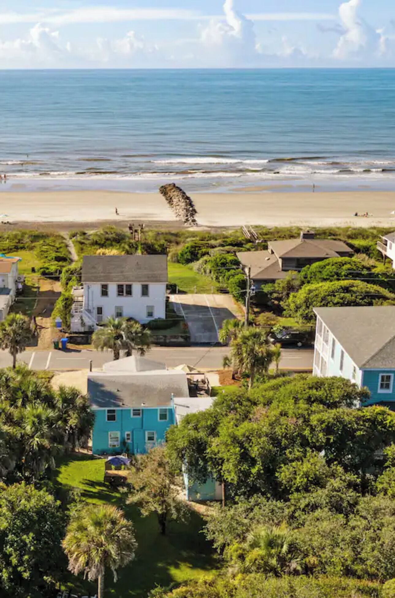 A coastal residential area with houses, a beach, and a clear sky.