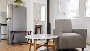 Una sala de estar moderna con un sillón gris, una mesa blanca y un televisor integrado.