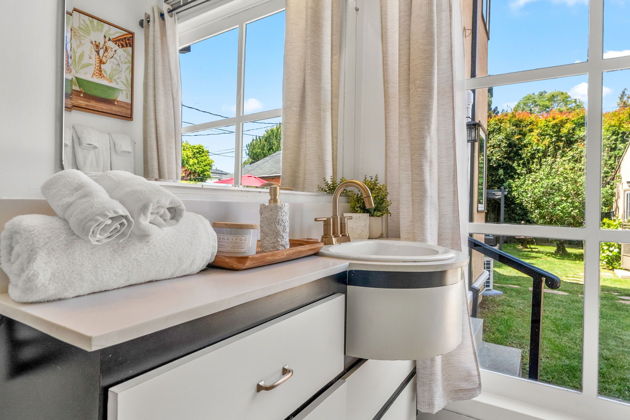 A bathroom with a window, a sink, a towel rack, and a mirror.