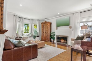 A living room with a fireplace, leather sofa, wooden coffee table, and a TV mounted on the wall.