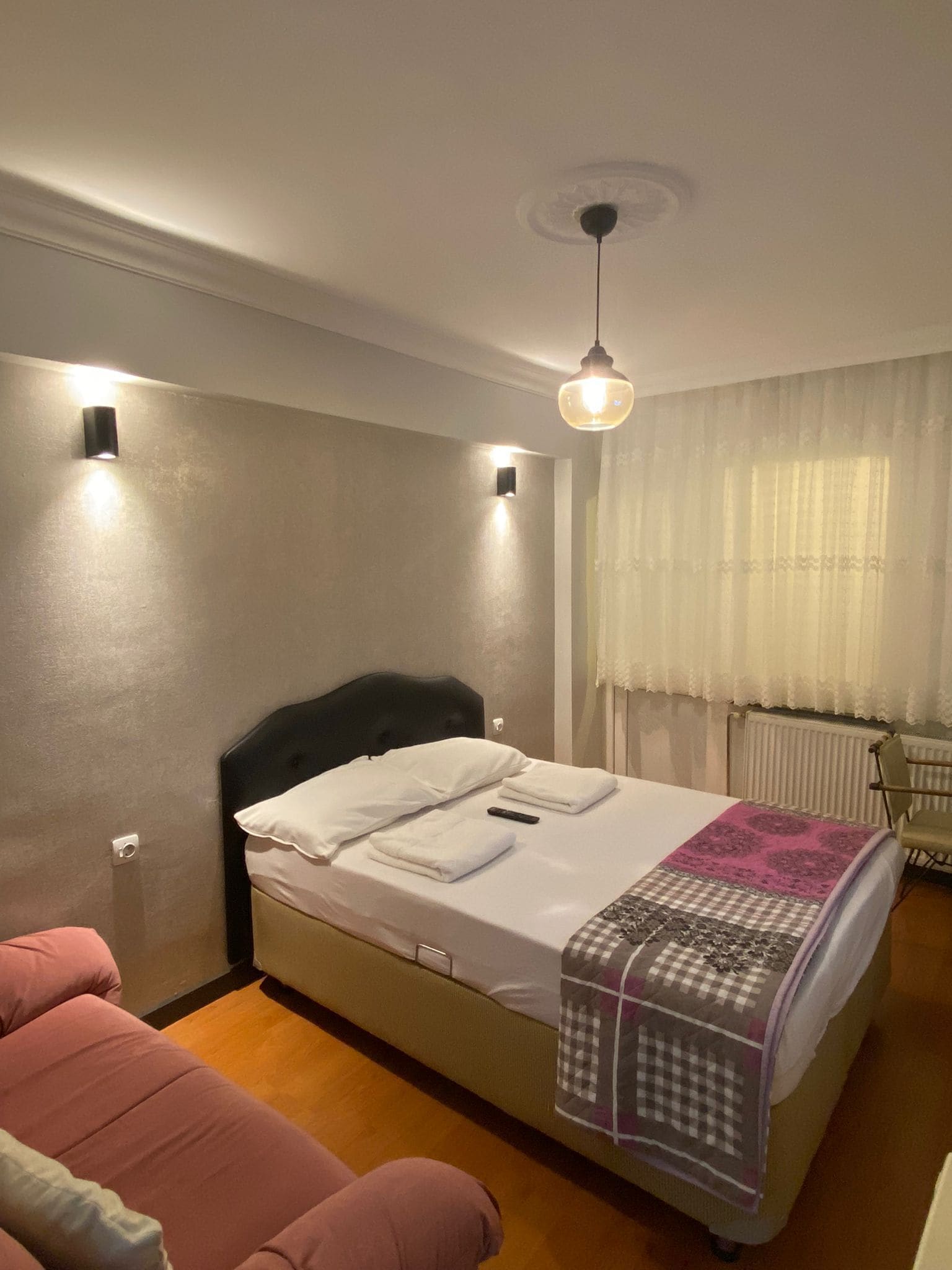 A bedroom with a bed, bedside tables, a chair, and a window with curtains.