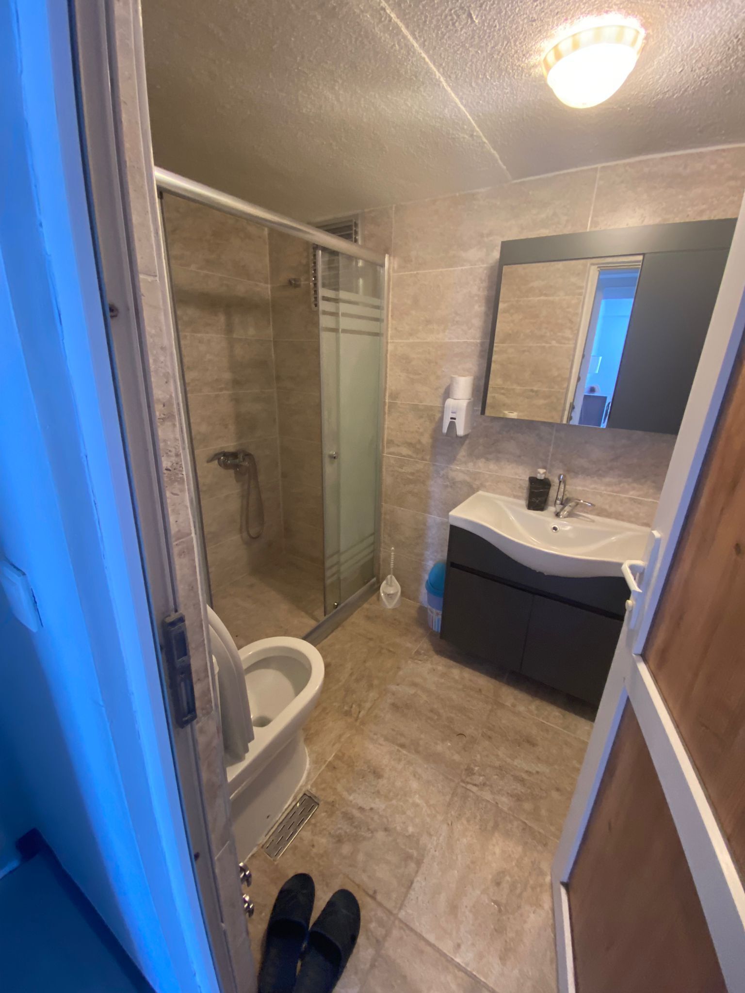 Un bany amb plat de dutxa tancat per vidre, un lavabo amb mirall i un vàter.