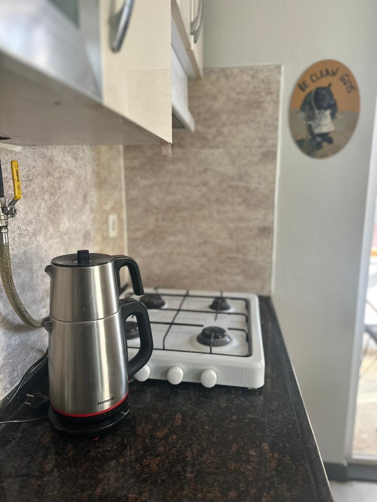 Una cucina con una caffettiera in acciaio inossidabile su un piano di lavoro in granito, un fornello a gas e un forno a incasso.