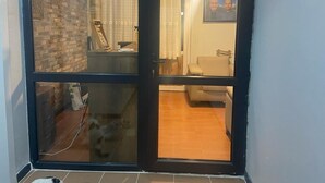 A room with a tiled floor, a brick wall, a wooden desk, a white chair, and a framed picture on the wall. - Mertcan Pansiyon (Karabük)