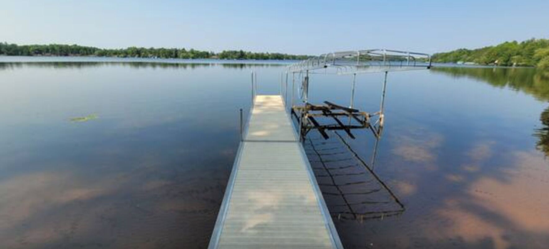 Un lago tranquilo con un muelle de madera que se adentra en el agua.